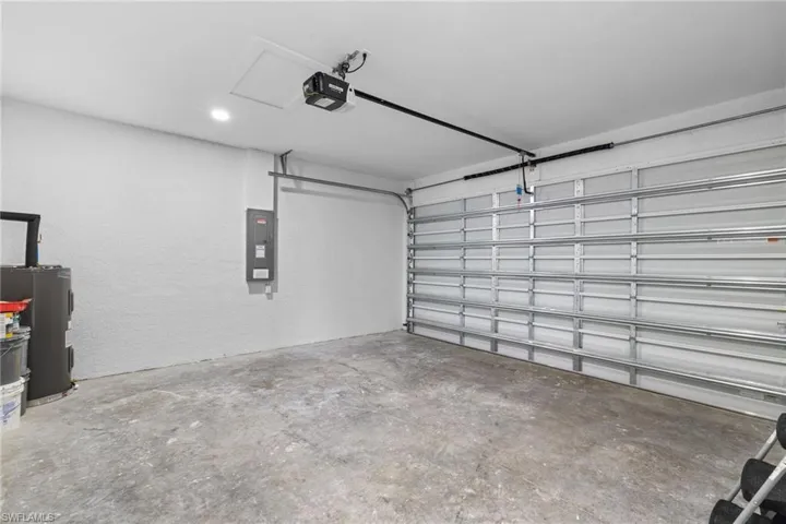 Garage featuring electric panel, a garage door opener, and a textured wall