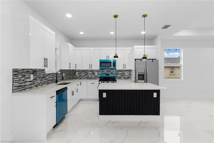 Kitchen with appliances with stainless steel finishes, a sink, a kitchen island, backsplash, and white cabinets