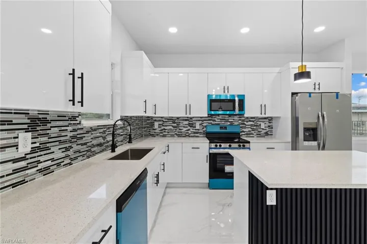 Kitchen with stainless steel appliances, a sink, decorative backsplash, white cabinets, and recessed lighting