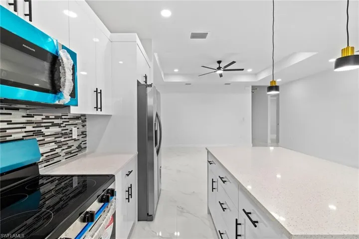 Kitchen with stainless steel appliances, light marble finish flooring, recessed lighting, tasteful backsplash, and a ceiling fan