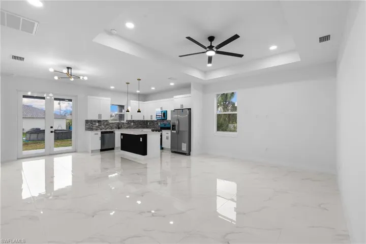 Kitchen with appliances with stainless steel finishes, open floor plan, a raised ceiling, a kitchen island, and healthy amount of natural light