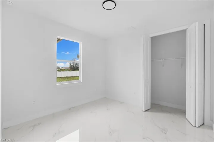 Unfurnished bedroom featuring baseboards, marble finish flooring, and a closet
