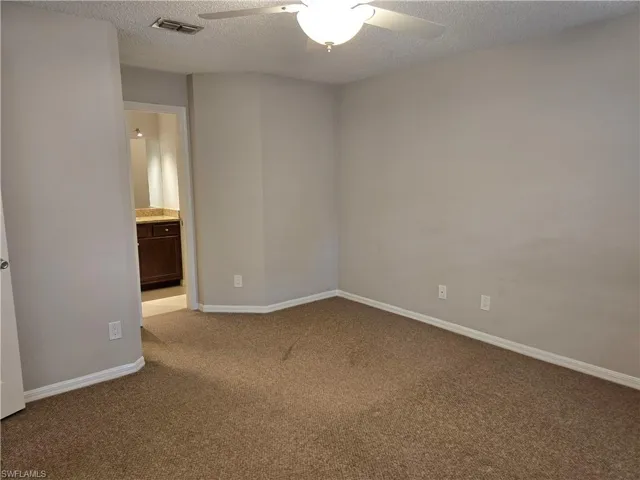 Carpeted empty room featuring a ceiling fan and baseboards