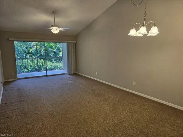 Living/Dining room featuring a chandelier, vaulted ceiling, baseboards, and a ceiling fan.