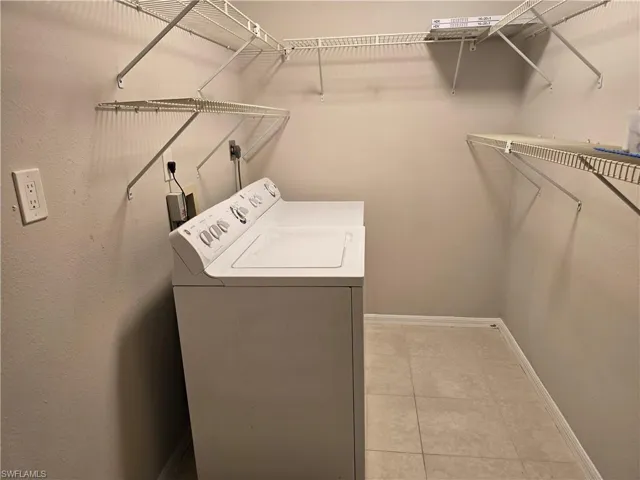 Laundry room featuring washer / clothes dryer, baseboards, and light tile patterned floors