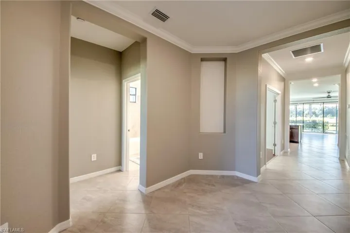 Hallway with crown molding and light tile patterned floors