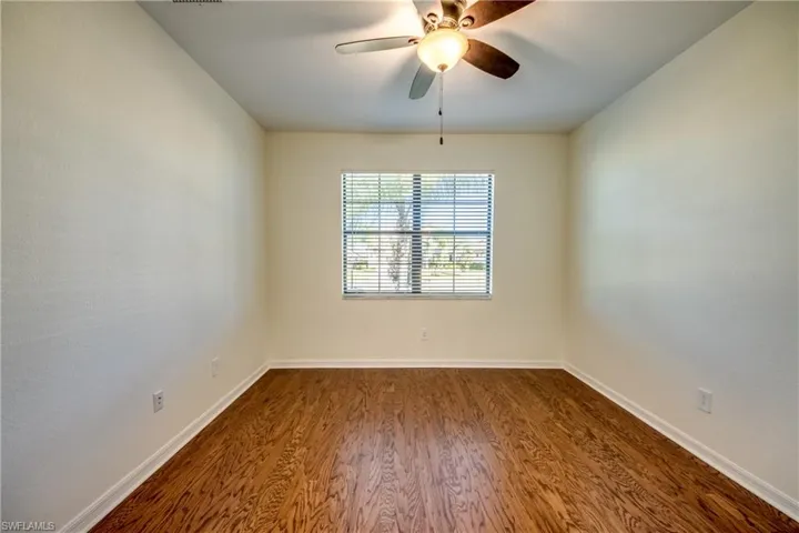 Unfurnished room featuring dark wood-style flooring and a ceiling fan