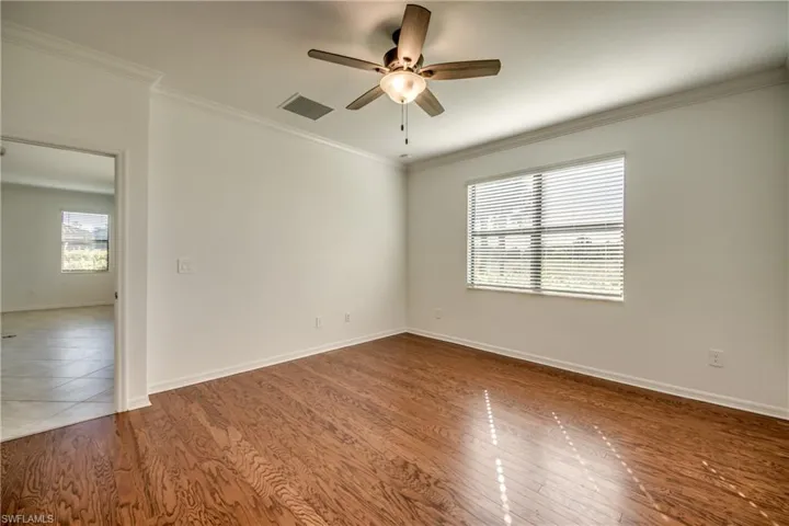 Empty room with crown molding, wood finished floors, and ceiling fan