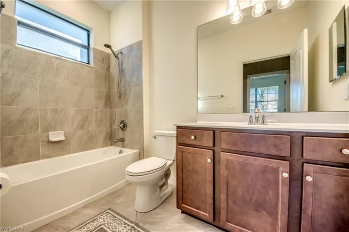 Full bathroom with healthy amount of natural light, shower / washtub combination, vanity, and light tile patterned flooring