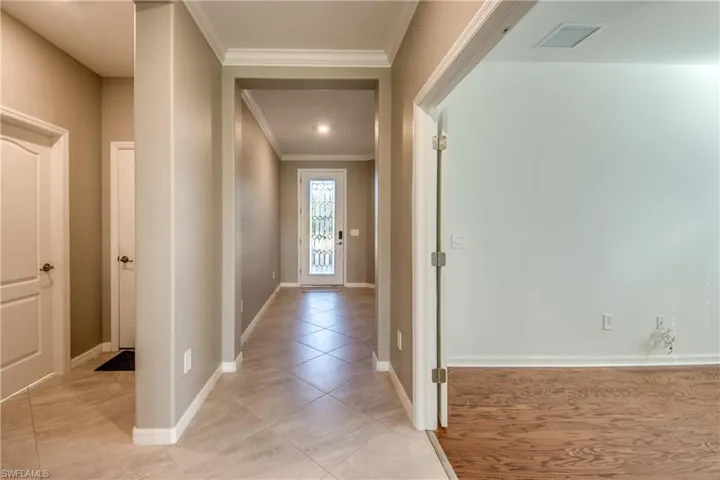Corridor featuring crown molding and light tile patterned floors