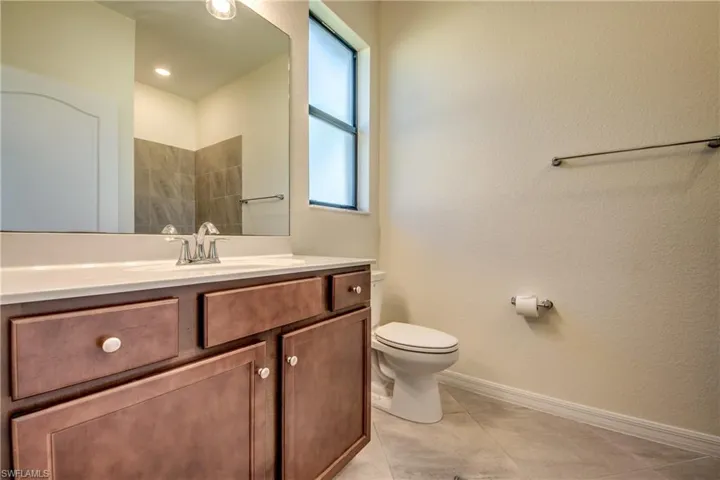 Full bathroom with vanity, light tile patterned flooring, and a textured wall