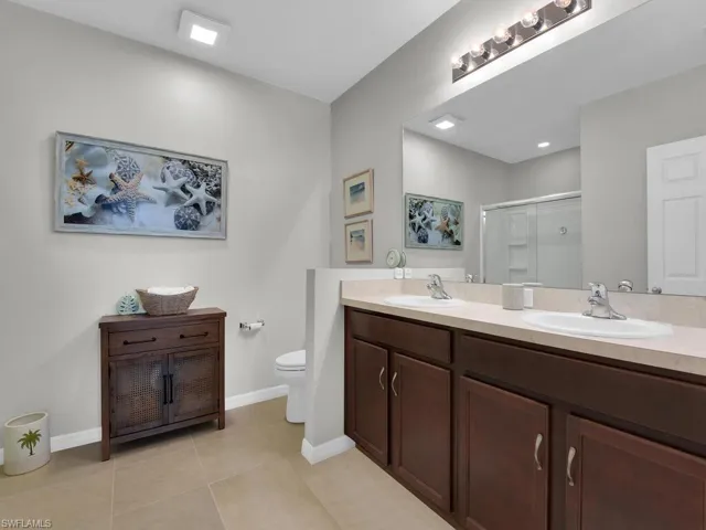 Bathroom with an enclosed shower, vanity, toilet, and tile patterned floors