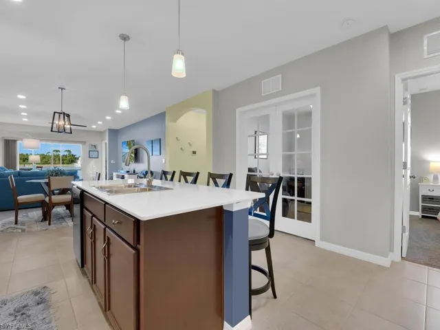 Kitchen with pendant lighting, a kitchen island with sink, sink, light tile patterned floors, and a breakfast bar area