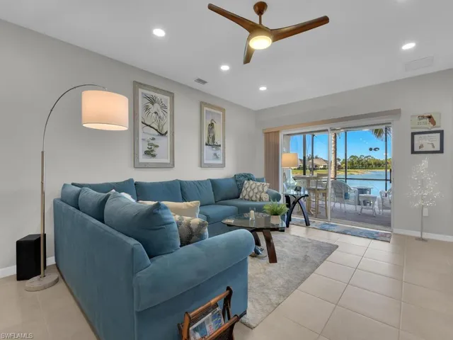 Living room with ceiling fan, light tile patterned flooring, and a water view