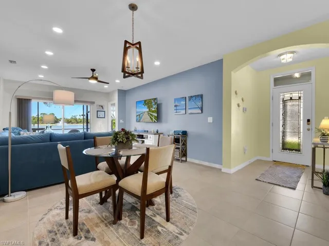 Tiled dining room featuring ceiling fan with notable chandelier