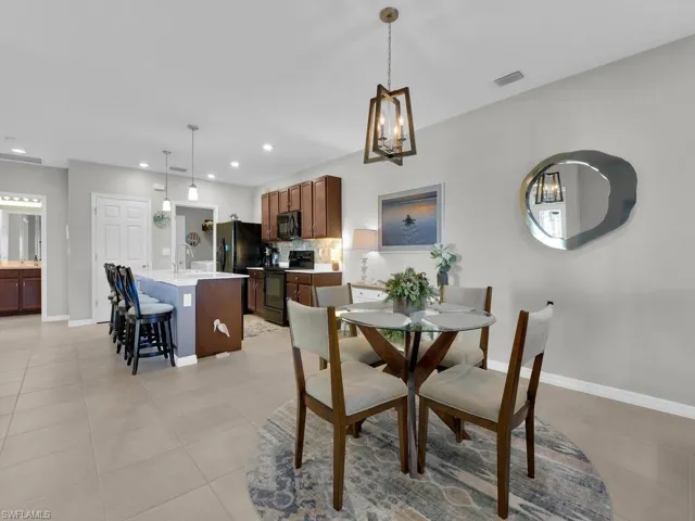 Dining area with sink, light tile patterned floors, and a notable chandelier