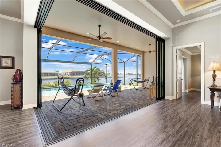 Doorway with ceiling fan, crown molding, a water view, and dark hardwood / wood-style floors