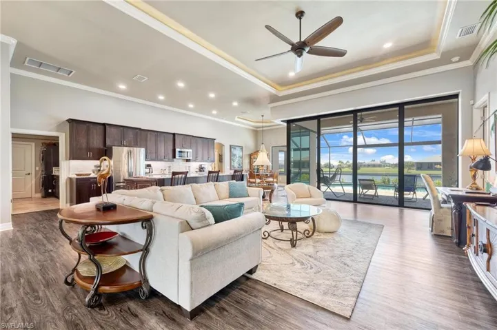 Living room with ceiling fan, crown molding, dark hardwood / wood-style flooring, and a raised ceiling