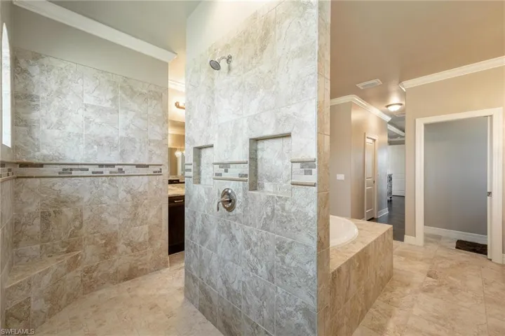 Primary Bathroom with shower with separate bathtub, tile walls, ornamental molding, tile patterned flooring, and vanity
