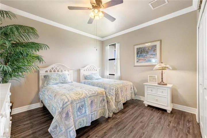 Bedroom featuring ceiling fan, dark wood-type flooring, and ornamental molding