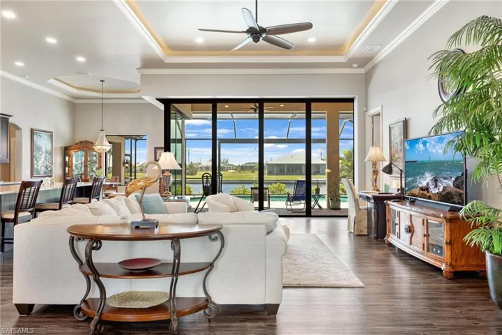 Living room featuring crown molding, dark hardwood / wood-style flooring, ceiling fan, french doors, and a raised ceiling