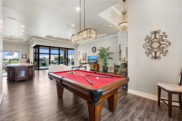 Recreation room with hardwood / wood-style floors, ornamental molding, pool table, and a tray ceiling