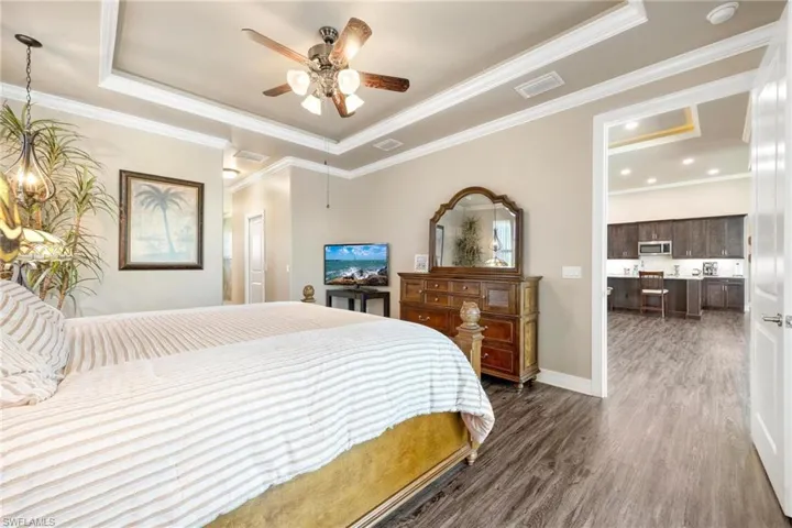 Primary Bedroom with a raised ceiling, dark hardwood / wood-style floors, and ornamental molding