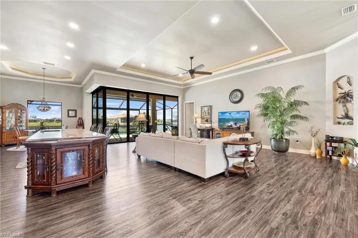 Living room with ceiling fan, dark wood-type flooring, and a tray ceiling