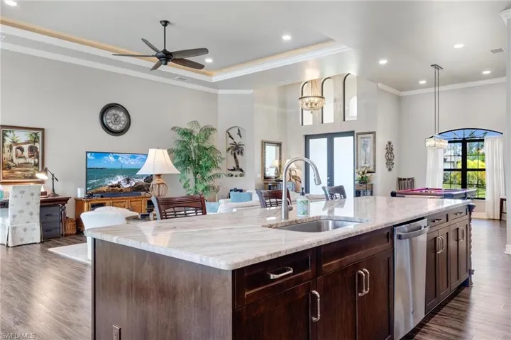 Kitchen featuring dark wood-type flooring, sink, light stone counters, and dishwasher