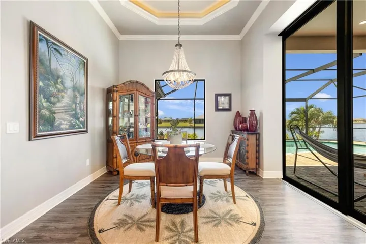 Dining area with a chandelier, a tray ceiling, hardwood / wood-style flooring, and a healthy amount of sunlight