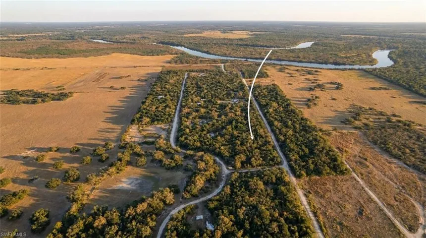 Expansive aerial view showcasing vast undeveloped land with natural vegetation and distant winding river