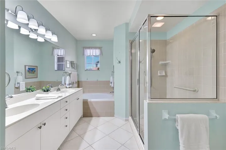 Primary en-suite bathroom with two sinks, soaker tub, walk-in shower, and lovely window with natural light flowing through!