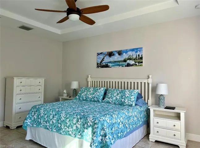 Bedroom featuring tile floors, ceiling fan, and a tray ceiling