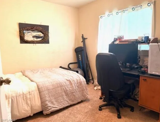 Bedroom with light colored carpet and a desk