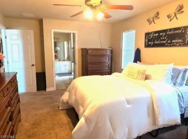 Bedroom with carpet flooring, a ceiling fan, and ensuite bathroom