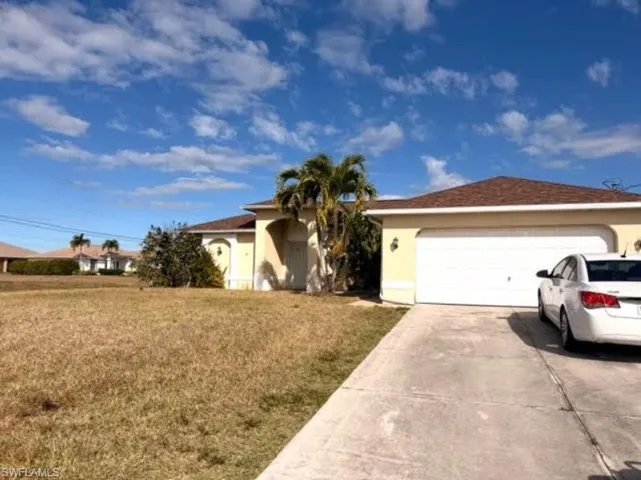 Ranch-style house with a front lawn, driveway, stucco siding, and an attached garage