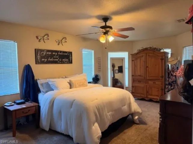 Bedroom with a ceiling fan and light carpet