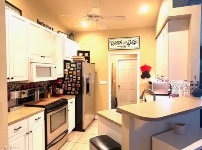 Kitchen with decorative backsplash, stainless steel appliances, a kitchen breakfast bar, a peninsula, and light countertops