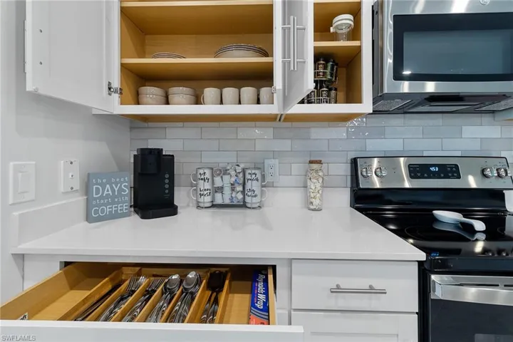 Kitchen with stainless steel appliances, white cabinets, and backsplash