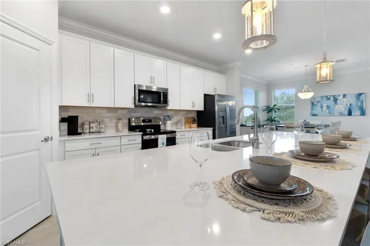 Kitchen with white cabinets, a center island with sink, appliances with stainless steel finishes, and pendant lighting