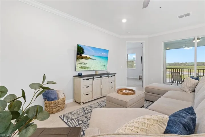 Living room featuring crown molding, ceiling fan, and light tile floors