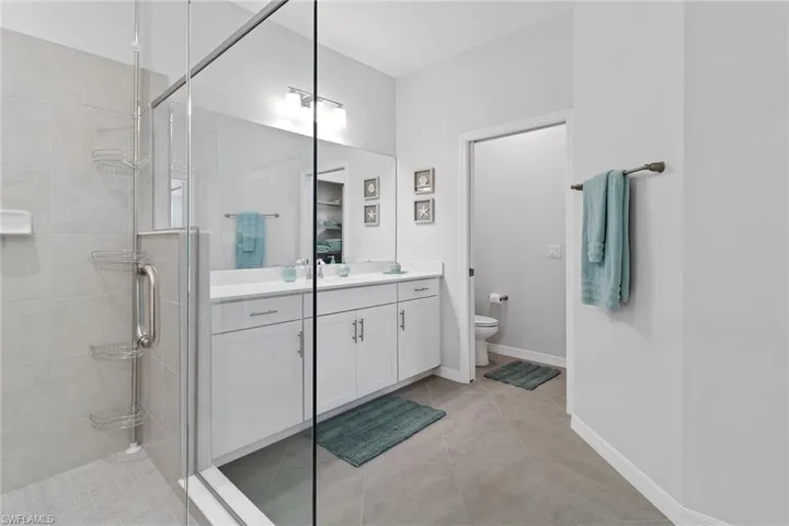 Bathroom with walk in shower, tile flooring, toilet, and vanity
