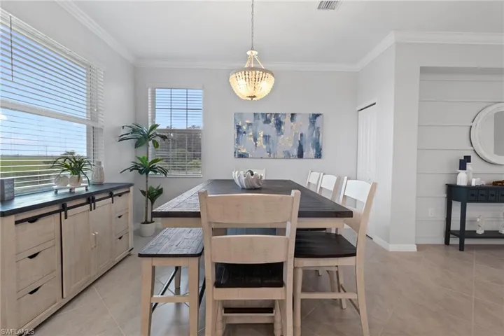 Tiled dining space featuring a notable chandelier and crown molding