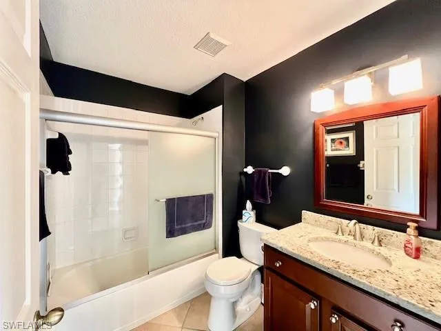 Bathroom featuring tile patterned flooring, vaulted ceiling, and vanity