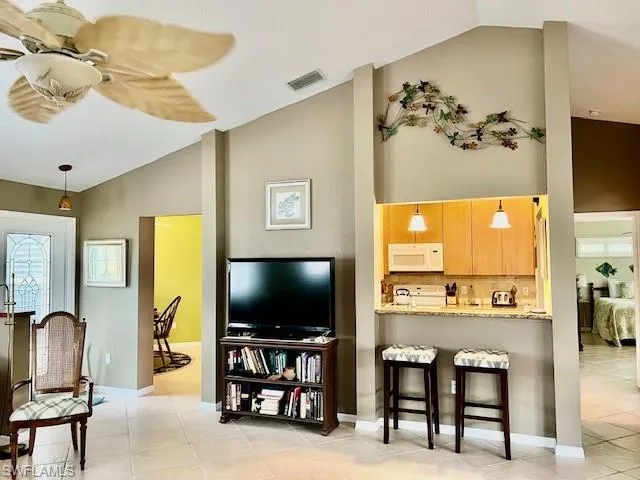 Tiled living room with lofted ceiling and ceiling fan
