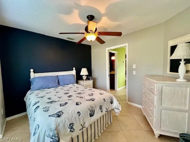 Tiled bedroom featuring ceiling fan and a textured ceiling