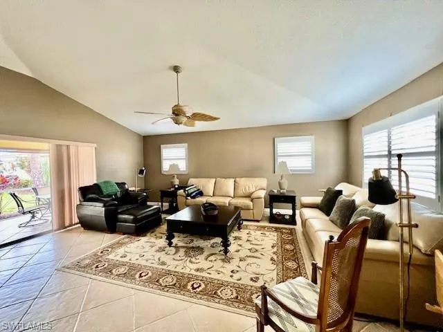 Living room with a healthy amount of sunlight, ceiling fan, vaulted ceiling, and light tile patterned floors