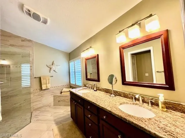 Bathroom with lofted ceiling, tile patterned flooring, a textured ceiling, and vanity