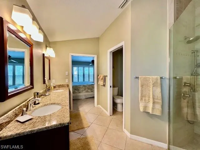 Bathroom with lofted ceiling, toilet, tile patterned floors, a shower with door, and vanity