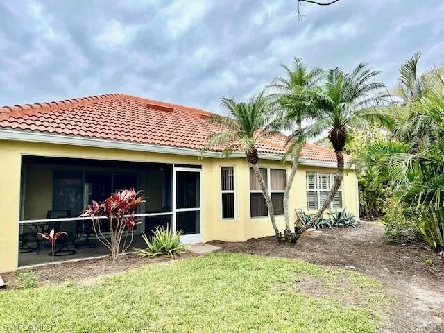 Rear view of property with a yard and a sunroom